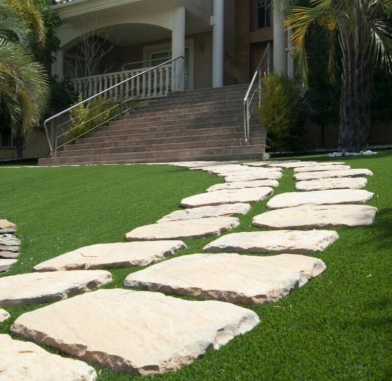 Camino de piedra natural integrado en un jardín de césped artificial