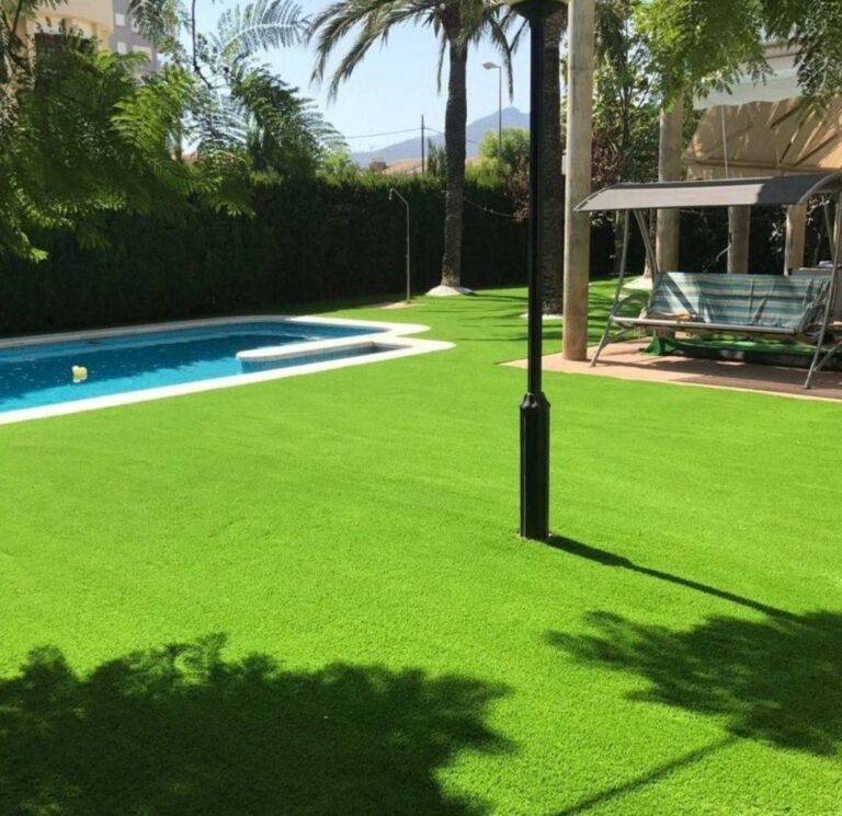 Jardín con césped artificial, palmeras y piscina
